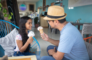 father playing with his daughter while eating gelato, dad putting ice cream on his child girl having fun