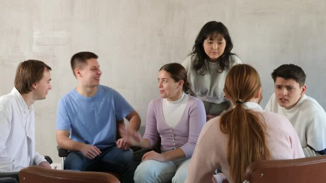 Group of cheerful carefree young students relaxing and chatting amicably during recess between lectures in auditorium. High quality FullHD footage