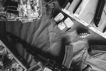Military body armor, ammunition, F-1 grenades and a Kalashnikov assault rifle on a brown...
