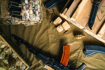 Military body armor, ammunition, F-1 grenades and a Kalashnikov assault rifle on a brown...