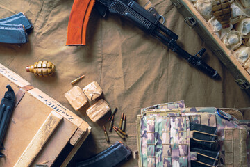 Military body armor, ammunition, F-1 grenades and a Kalashnikov assault rifle on a brown...