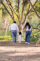 Naklejka na ściany i meble Family members holding hands and walking backwards in a park together family