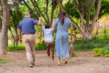 Family members holding hands and walking backwards in a park together family