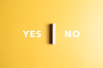 Yes or No words on a yellow background with a wooden block in the middle. Make choices between...