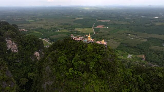 Golden Buddha statue at Tiger Cave Temple Wat Tham Sua in Krabi Thailand. Footage filmed from the sky in 4k
