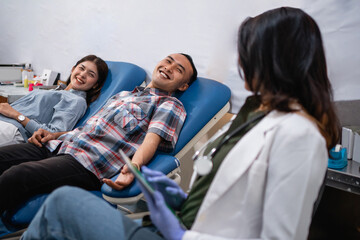 two patients lying in bed during a blood transfusion by a doctor at a hospital