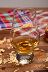 Tasting of different Scotch whiskies strong alcoholic drinks, drum of whiskey and colorful Scotch tartan on background close up