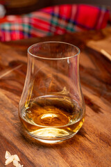 Tasting of different Scotch whiskies strong alcoholic drinks, drum of whiskey and colorful Scotch tartan on background close up