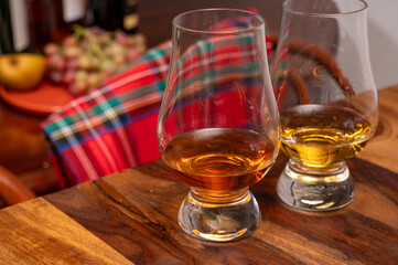Tasting of different Scotch whiskies strong alcoholic drinks, drum of whiskey and colorful Scotch tartan on background close up