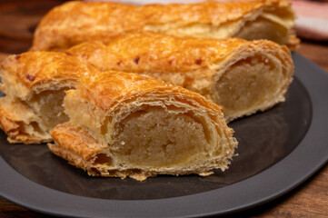 Fresh baked Dutch filled spicy cookies from puff pastry with almonds on black board close up