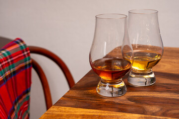 Tasting of different Scotch whiskies strong alcoholic drinks, drum of whiskey and colorful Scotch tartan on background close up