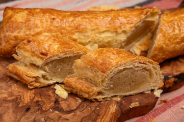 Fresh baked Dutch filled spicy cookies from puff pastry with almonds on wooden board close up