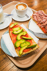Avocado toast and coffee served on a wooden tray.