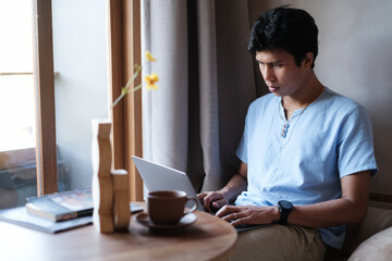 Asian man wearing casual outfit looking serious while checking mail, news, social networks, working...