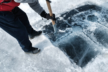 Man sawing an ice hole for diving - obrazy, fototapety, plakaty