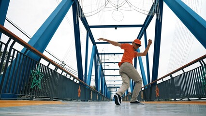 Skilled asian hipster perform footstep at bridge with low angle camera while wearing stylish cloth. Professional stress dancer practice break dancing. Modern lifestyle. Outdoor sport 2024. Sprightly.
