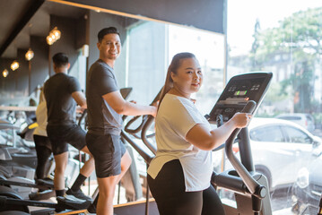 asian couple working out together in a gymnasium for cardio exercise