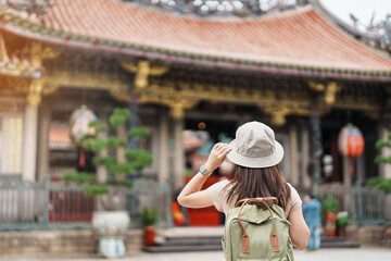 Fototapeta premium woman traveler visiting in Taiwan, Tourist with hat sightseeing in Longshan Temple, Chinese folk religious temple in Wanhua District, Taipei City. landmark and popular. Travel and Vacation concept