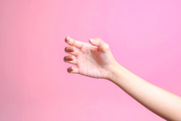 Female hand holding something like a bottle or can isolated on pink background  - obrazy, fototapety, plakaty