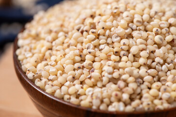 Sorghum seeds in plate on wooden table. Whole seeds of Sorghum Moench