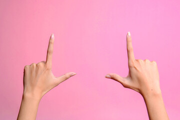 Woman's hand making shooting gun gesture. Hands pointing up with two fingers