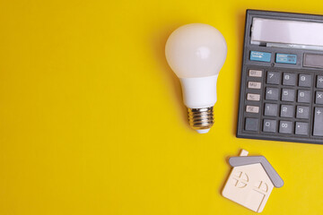 Calculator, light bulb and house symbol on yellow background. The concept of calculating energy...
