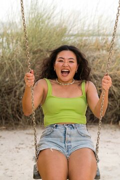Asian woman sitting on the swings against yellow wall background