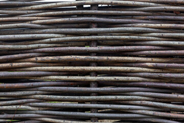 Part of a fence made of wooden branches. Aesthetics and ecology. Space for text. Background.