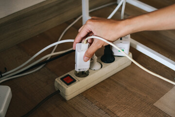 Man hand inserting plug into extension cord in room. Electrical concept