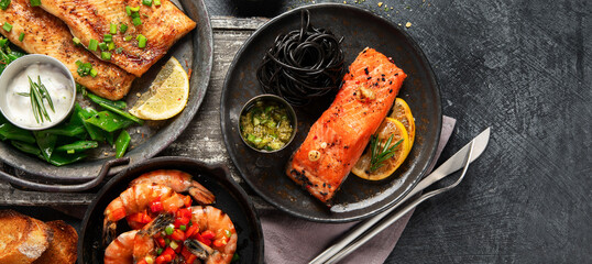 Grilled salmon fish fillet with lemon and strimps. Sea food dishes assorty. Healthy concept