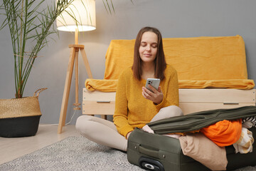 Stylish tourist lifestyle. Packed for a journey. Caucasian young adult woman packing suitcase at...