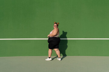 Full length portrait of a plump woman against green background