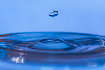 Blue colored water forms beautiful drops when falling from a certain height