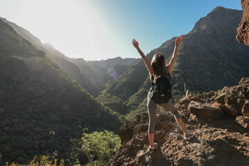 back view of young woman Hiker Victory Pose with raised arms at Anaga National Park, Tenerife with...