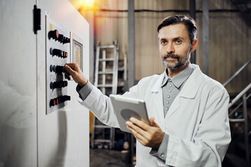 Engineer with tablet working on machinery at polymer factory