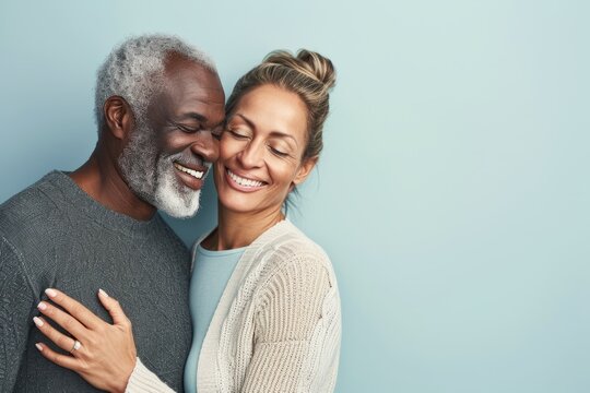 Happy Couple In Love. Smiling Mature Man And Woman Embracing Each Other And Looking At Camera While Standing Against Blue Background