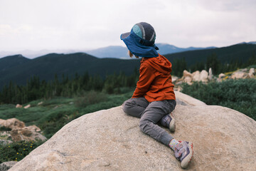 Girl sitting on a rock, enjoying the view of the mountain
