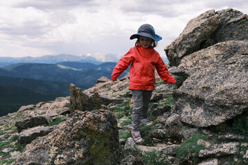 Young girl climbing rocky mountain ridge, enjoying outdoor adventure