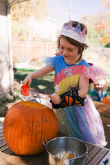 Girl carving pumpkin, smiling in sunny autumn celebration