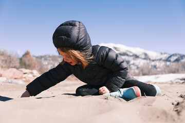 Fototapeta na wymiar A child playing in the sand on a winter day
