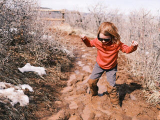 Kid with sunglasses walks on a muddy path