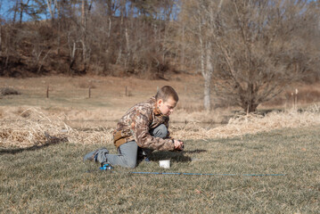 Naklejka na ściany i meble Boy putting work on fishing rod near pond
