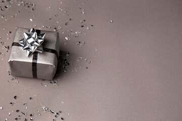 grey gift box with silver ribbon on a grey background with copy space for text.