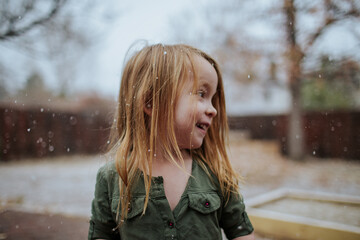 Happy preschool girl standing outside in light snow