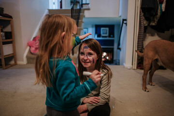 Young happy girls using face paint on each other