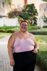 Fototapeta premium Portrait of a plump woman wearing sports clothing standing outdoors posing