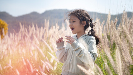 Little girl in a meadow enjoy nature on meadow with happy face expression smiling outdoors enjoying warm sunny summer day.