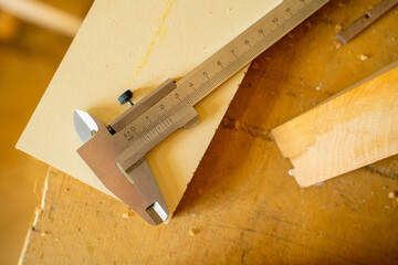 Close-up of a caliper lying on a table in a carpenter's workshop