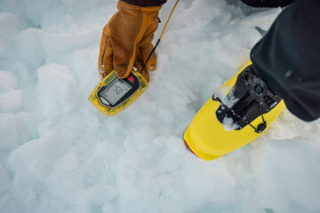 Person holding a modern avalanche beacon in his hands. Off piste skier displaying avalanche beacon and how to use it. Lavine prevention device, beacon to find a person gliding on snow.