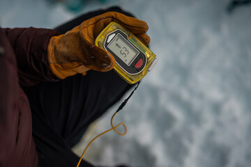 Person holding a modern avalanche beacon in his hands. Off piste skier displaying avalanche beacon and how to use it. Lavine prevention device, beacon to find a person.